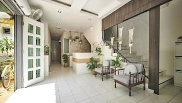 A modern interior with a reception desk, seating area, staircase, and a view of the outside.