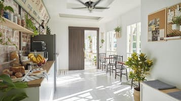 A bright kitchen with a counter displaying food items, a ceiling fan, and a view into the dining area.