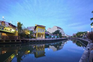 A canal with buildings reflecting on the water, a bridge, and street lamps. - Sleepy Nomad Hostel (Malacca City)