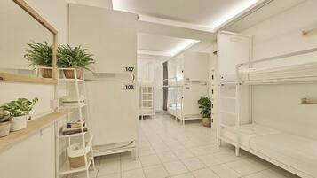 A hotel room with bunk beds, a white wardrobe, a ladder, and potted plants.