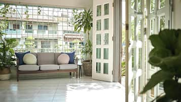 A balcony with a sofa, potted plants, and a view of buildings.