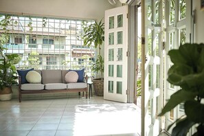 A balcony with a sofa, potted plants, and a view of buildings. - Sleepy Nomad Hostel (Malacca City)
