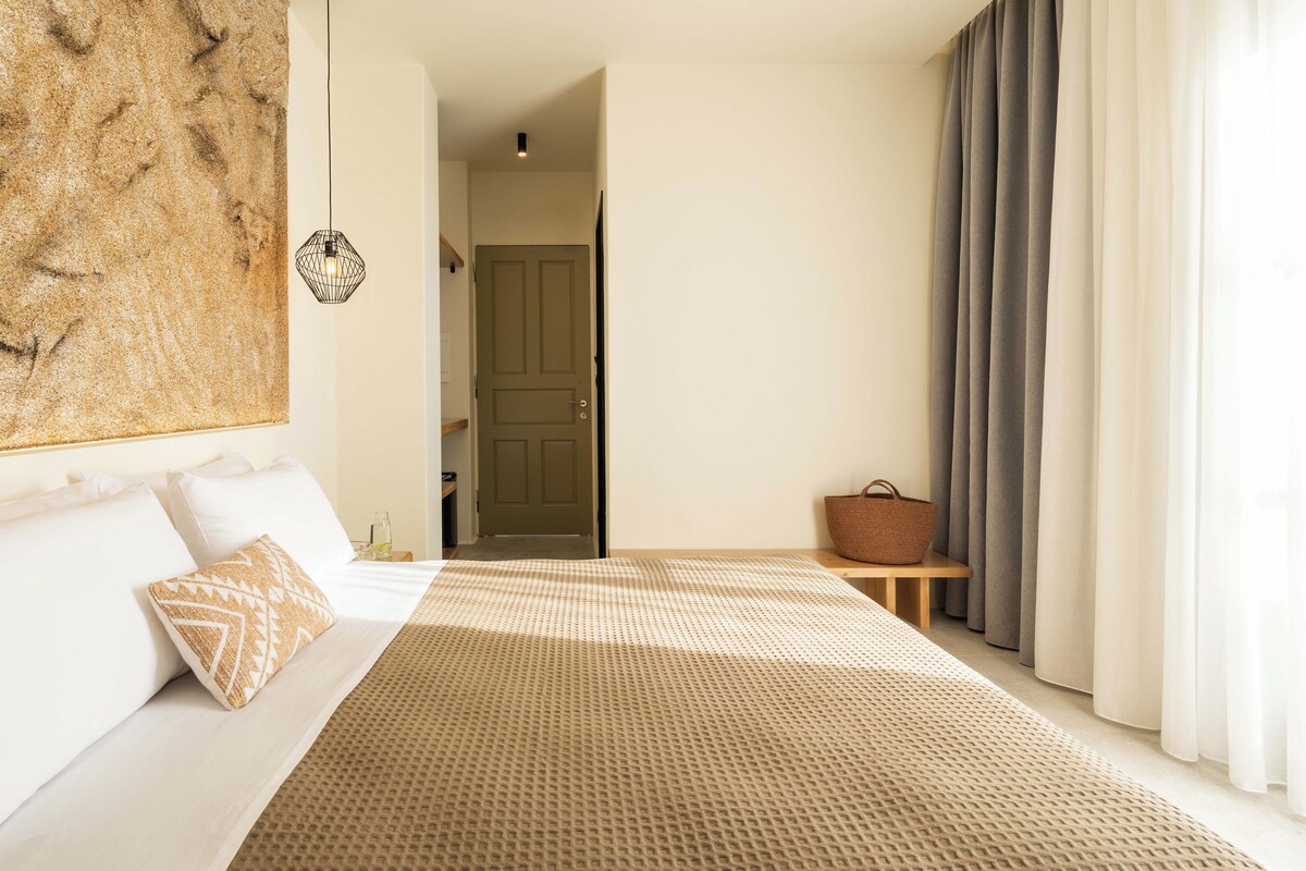 Un dormitorio con cama, mesita de noche, una obra de arte en la pared y una puerta.