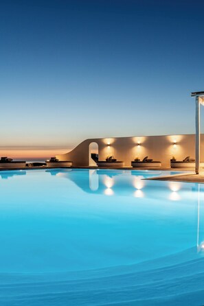 A swimming pool with a modern architectural backdrop, including a curved wall and seating areas. - Philosophy Of Mykonos (Mykonos)