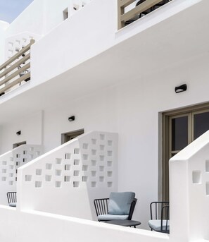 Um edifício branco com varanda, escadaria e janela.
