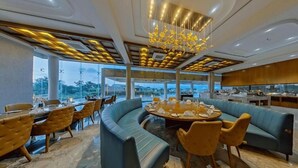 A modern dining area with a round table, blue sofas, and yellow chairs. - Araiya Gir,a Mavintara Resort (Talala)
