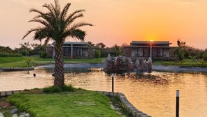 A modern building with a pool and a palm tree in the foreground. - Araiya Gir,a Mavintara Resort (Talala)
