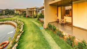 A modern residential building with a well-maintained lawn, a small pond, and outdoor seating area. - Araiya Gir,a Mavintara Resort (Talala)
