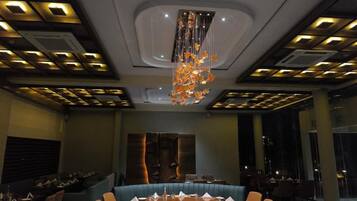 A conference room with a round table, blue upholstered chairs, and a chandelier.