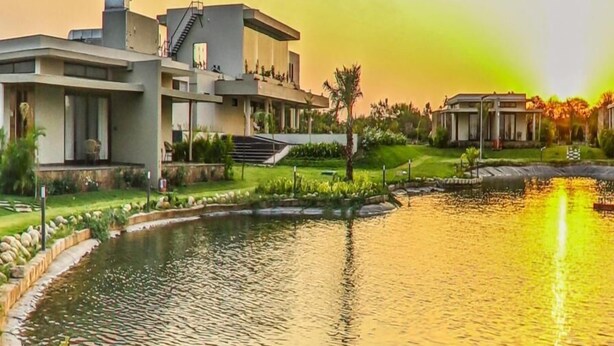 A modern building with a pool, surrounded by greenery and a sunset. - Araiya Gir,a Mavintara Resort (Talala)