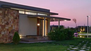 A modern house with a stone facade, a covered porch, and a well-maintained garden. - Araiya Gir,a Mavintara Resort (Talala)