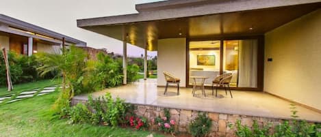 A modern house with a covered patio, stone retaining wall, and lush garden.
