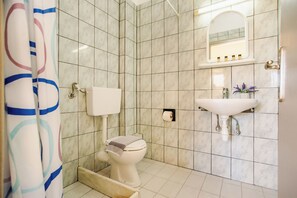A bathroom with a toilet, sink, and shower curtain. - Solena Studios Kavos (Corfu)
