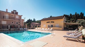 A swimming pool with lounge chairs, a building labeled "APODIME COMPLEX," and a clear blue sky. - Solena Studios Kavos (Corfu)