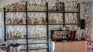 A bar area with shelves of liquor bottles, glasses, and a coffee machine. - Solena Studios Kavos (Corfu)