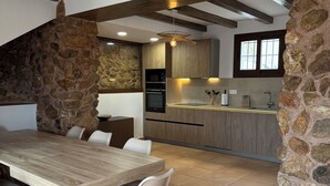 Eine moderne Küche mit Steinwänden, Holzbalken und einem Essbereich mit großem Tisch und Stühlen.