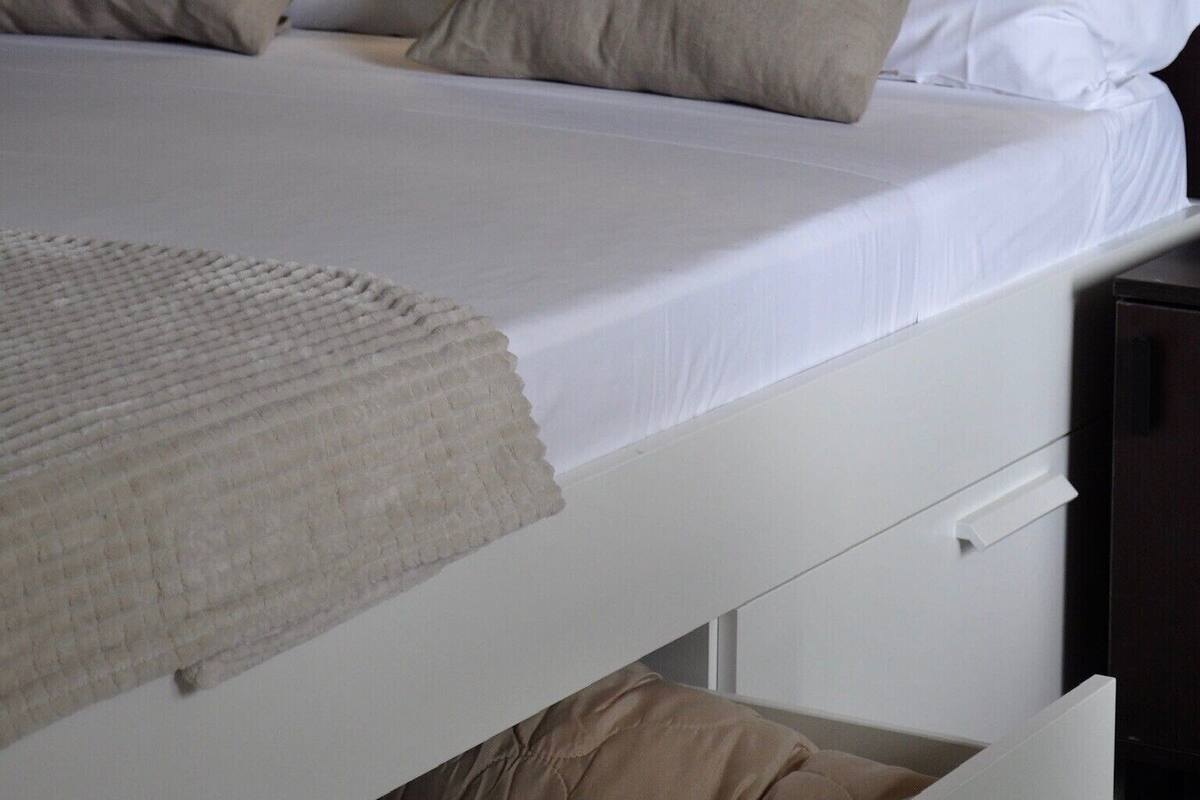 A neatly made bed with a headboard, pillows, and a blanket.