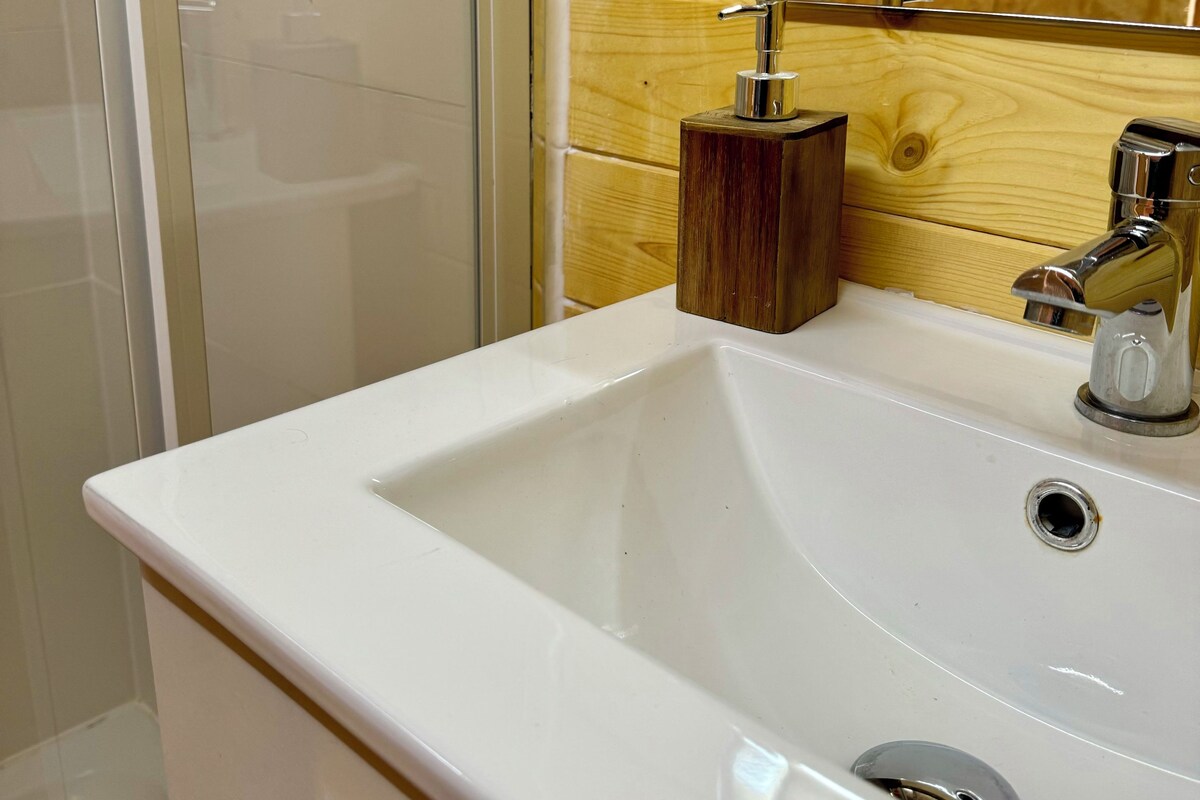 Un baño con un lavamanos blanco, un panel de pared de madera y un espejo.