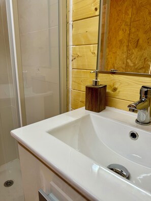 Un baño con un lavamanos blanco, un panel de pared de madera y un espejo.