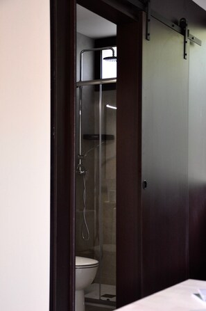 A bathroom with a glass-enclosed shower, a toilet, and a wooden door. - Bike Camp Algar Costa Blanca (Callosa d' En Sarria)
