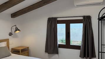 Un dormitorio con cama, lámpara de noche, ventana con cortinas, vigas de madera y unidad de aire acondicionado.