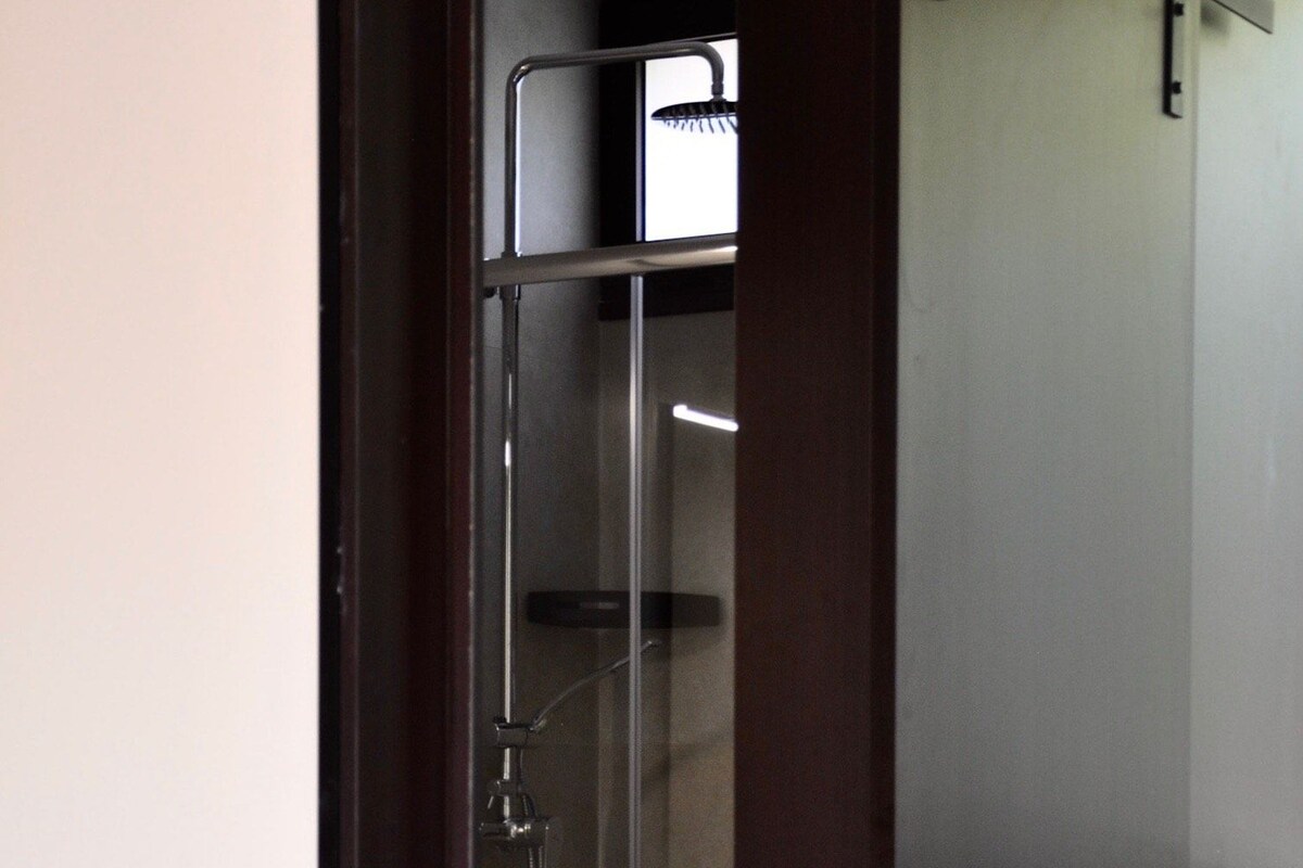 Un baño con ducha de vidrio, inodoro y puerta de madera.