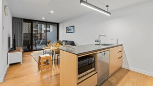 Una cocina moderna con una isla central, horno empotrado y pileta de acero inoxidable.
