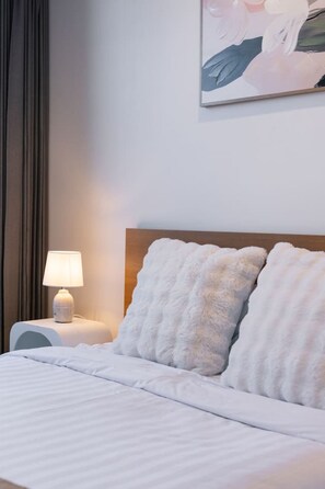 Une chambre d’hôtel avec un lit, une table de chevet avec une lampe et un tableau au mur.