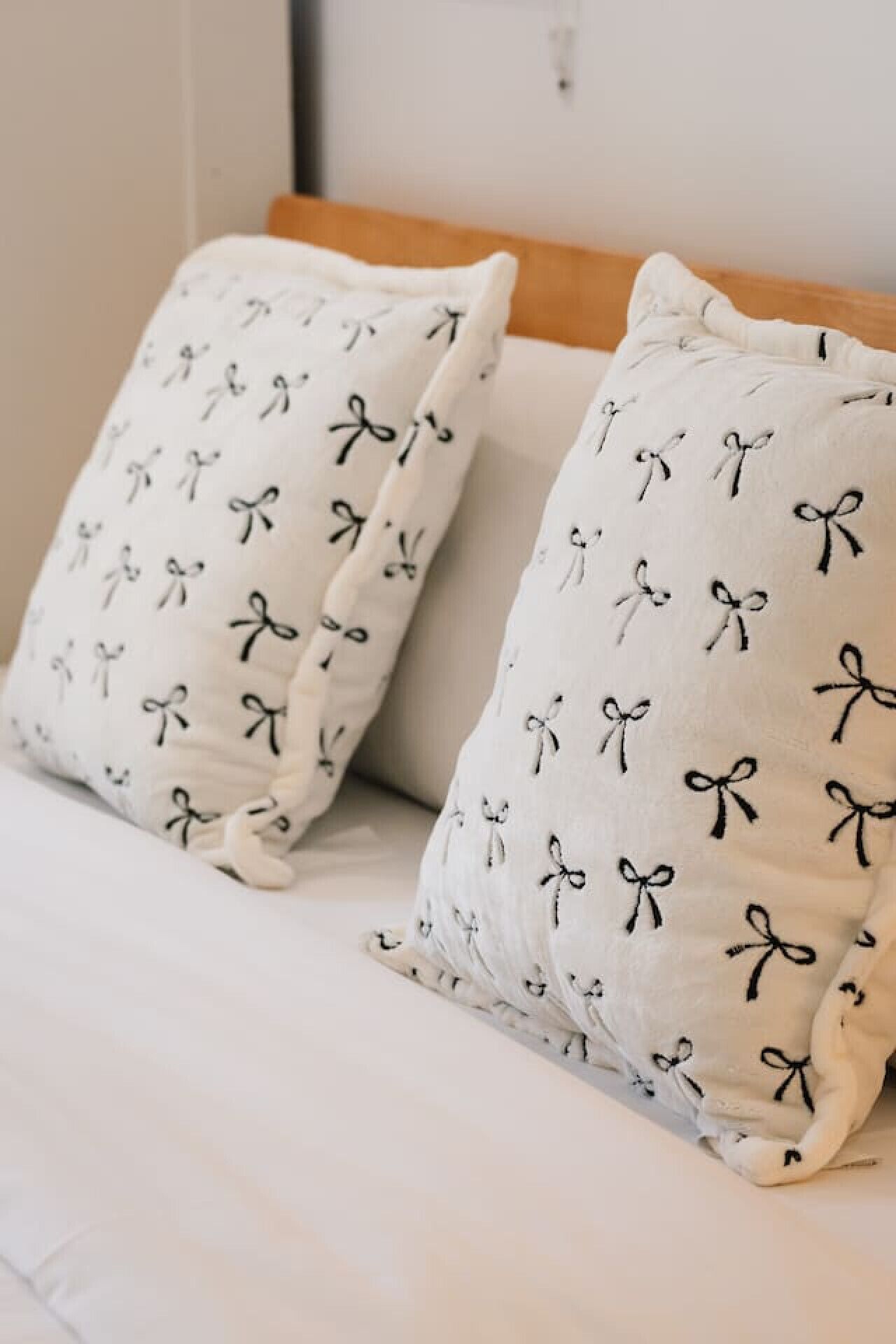 Two pillows with bow patterns on a bed.