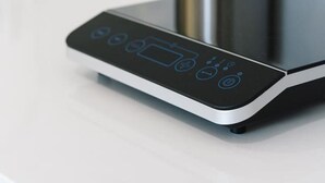 Une cuisine moderne dotée d’une plaque de cuisson à induction numérique et d’un porte-ustensiles en acier inoxydable.