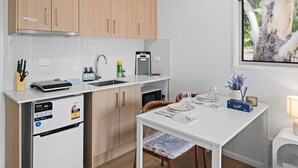 Eine kompakte Küche mit Holzschränken, einem integrierten Geschirrspüler, einer Kaffeemaschine und einem Essbereich mit Tisch für zwei Personen.