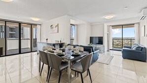 Ein modernes Apartment mit Essbereich, Wohnzimmer und Balkon mit Blick auf die Stadt.