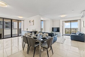 A modern apartment with a dining area, living room, and balcony with a city view. - Luxury High-Rise 2BR Apartment in Brisbane CBD (Brisbane City)