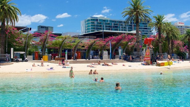 Ein Strandhotel mit Schwimmbad, Palmen und einem Rettungsschwimmerstand.