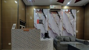 Un espace d’accueil avec un comptoir à motifs, un canapé gris et un mur en marbre.