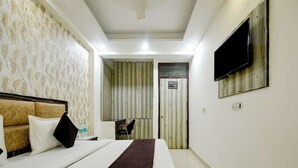 A hotel room with a bed, a TV mounted on the wall, and a bathroom door visible in the background. - Hotel Lookout Stay (New Delhi)