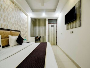 A hotel room with a bed, a TV mounted on the wall, and a bathroom door visible in the background. - Hotel Lookout Stay (New Delhi)