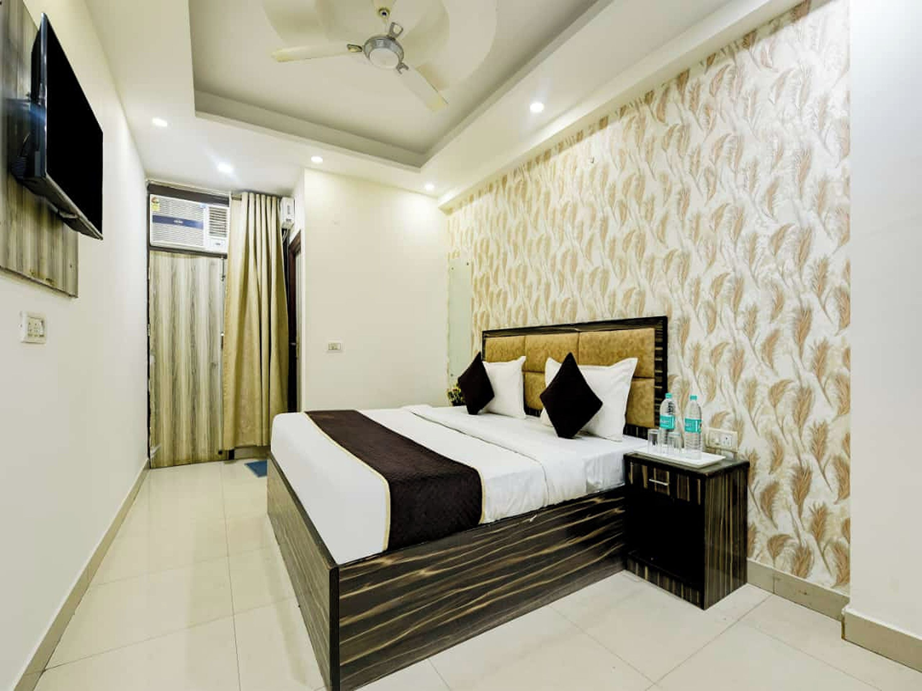 A hotel room with a bed, a nightstand, a TV, and a ceiling fan.