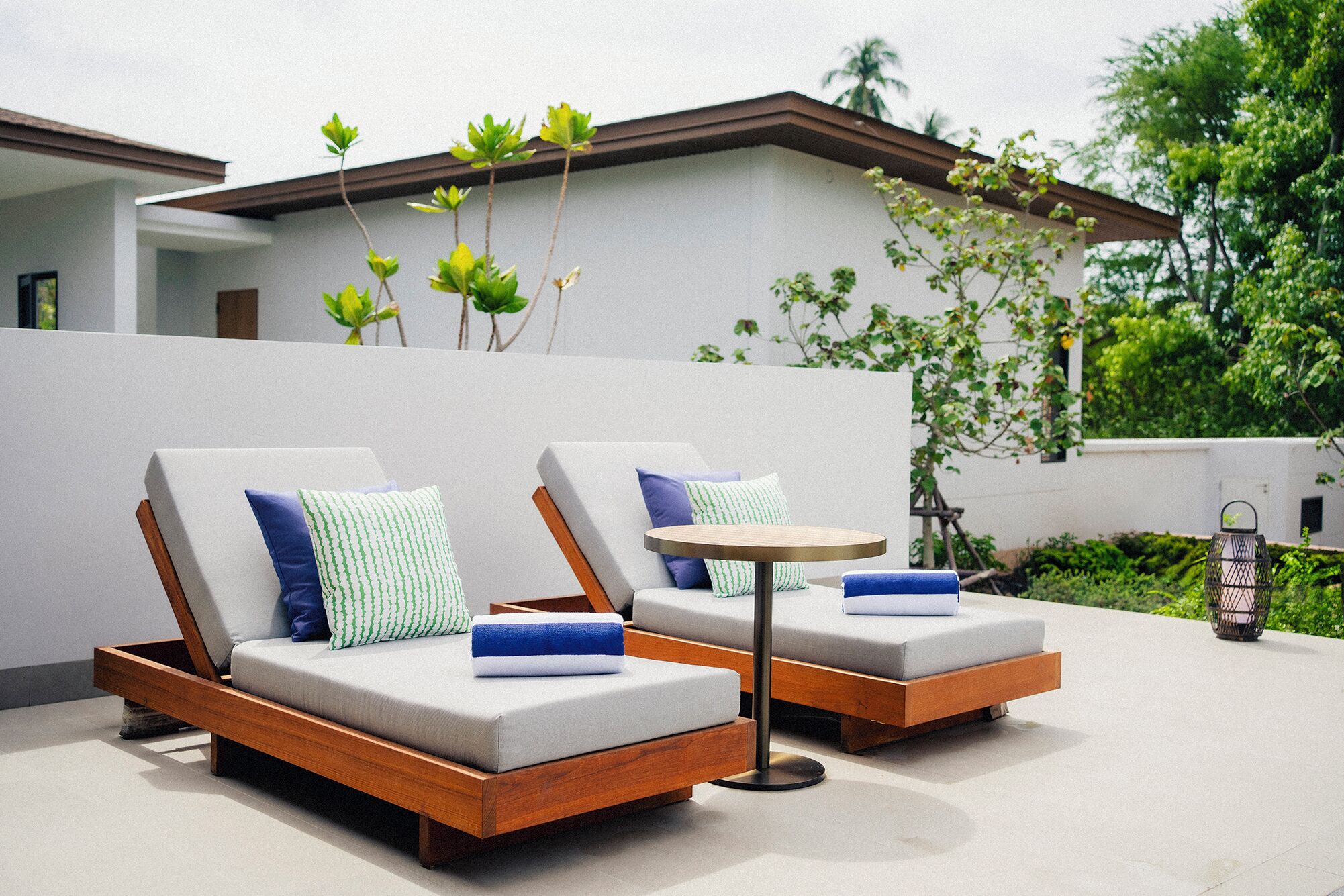 Two lounge chairs with cushions, a small round table, and a decorative lantern.