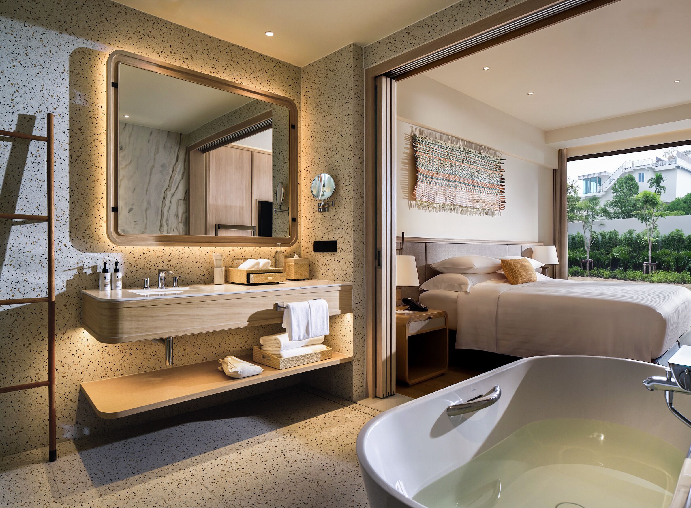 A modern bathroom with a freestanding bathtub, a large mirror, and a vanity with a towel rack.