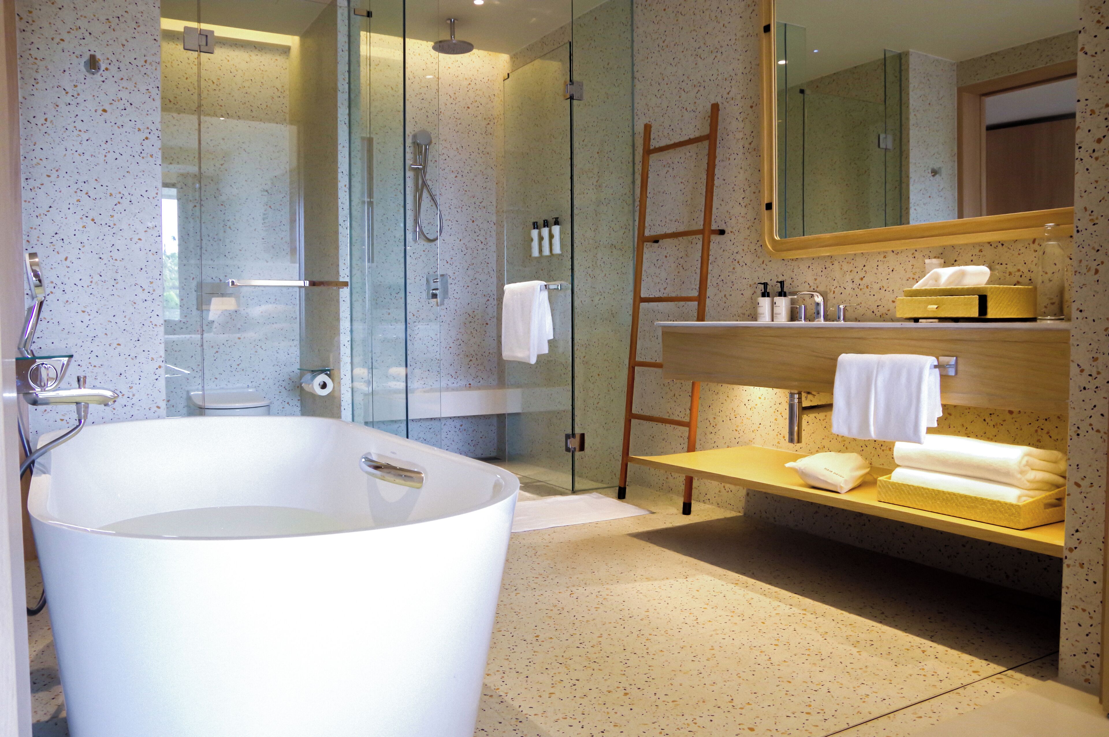 A modern bathroom with a freestanding bathtub, a glass-enclosed shower, a wooden vanity, and a large mirror.