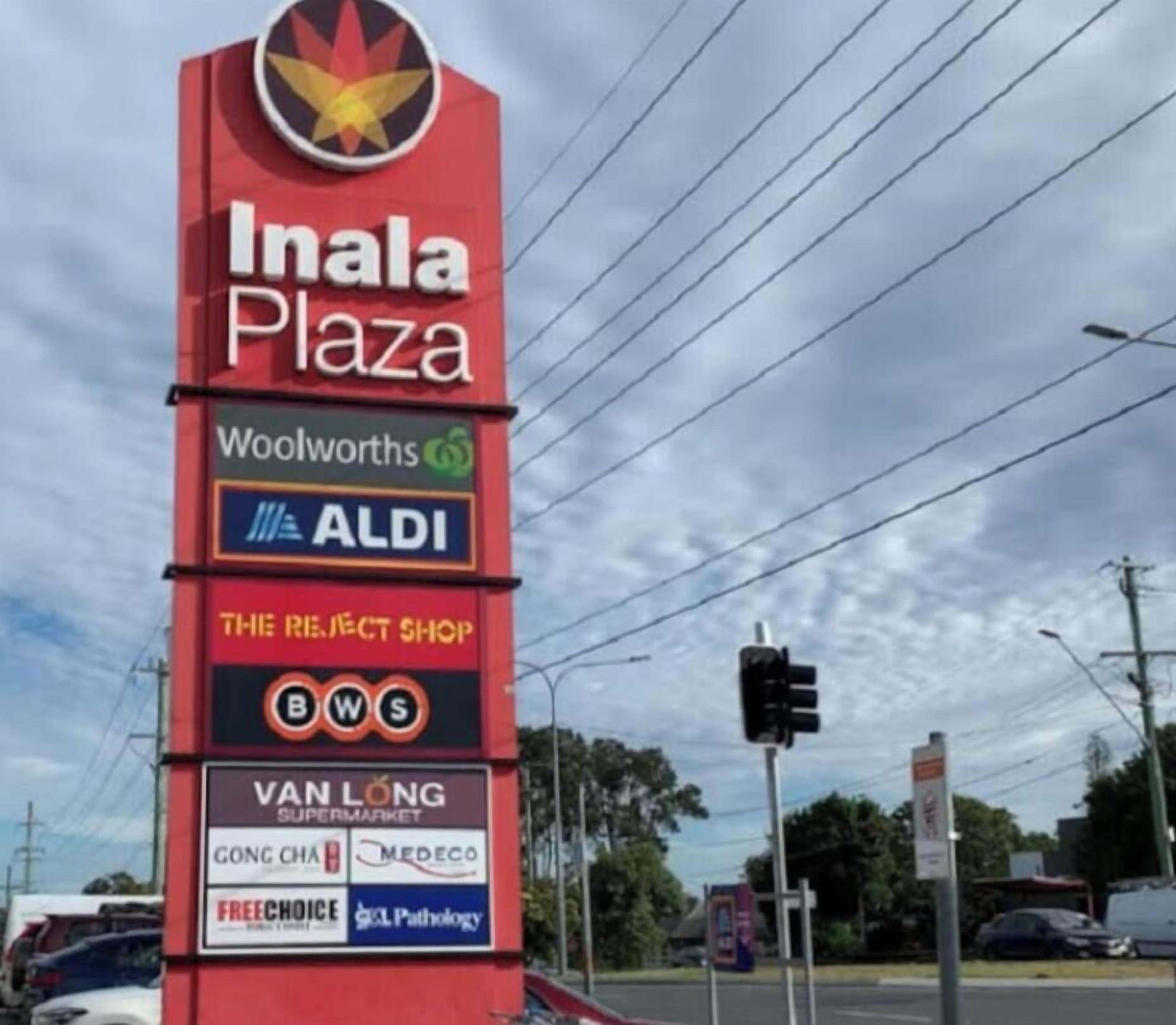 A signboard for Inala Plaza with various store names including Woolworths, ALDI, The Project Shop, BWS, Van Long Supermarket, Gong Cha, Medeco, FreeChoice, and GCL Pathology.