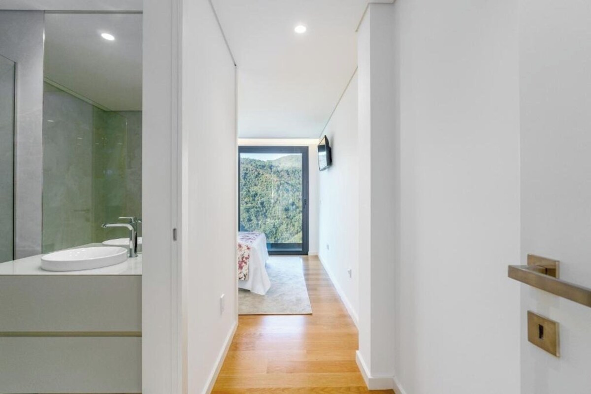 A modern bathroom with a large mirror, a sink, and a shower area.