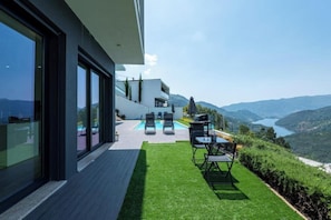 A modern outdoor patio with a pool, seating area, and a view of the surrounding landscape. - Gerês Paradise (Vieira do Minho)