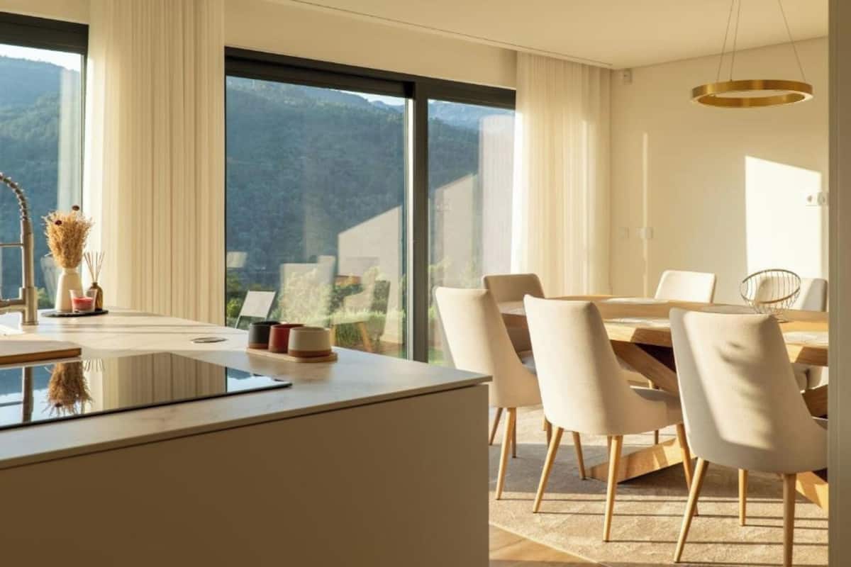 A modern dining area with a large window, a dining table, and chairs.