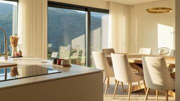 A modern dining area with a large window, a dining table, and chairs.