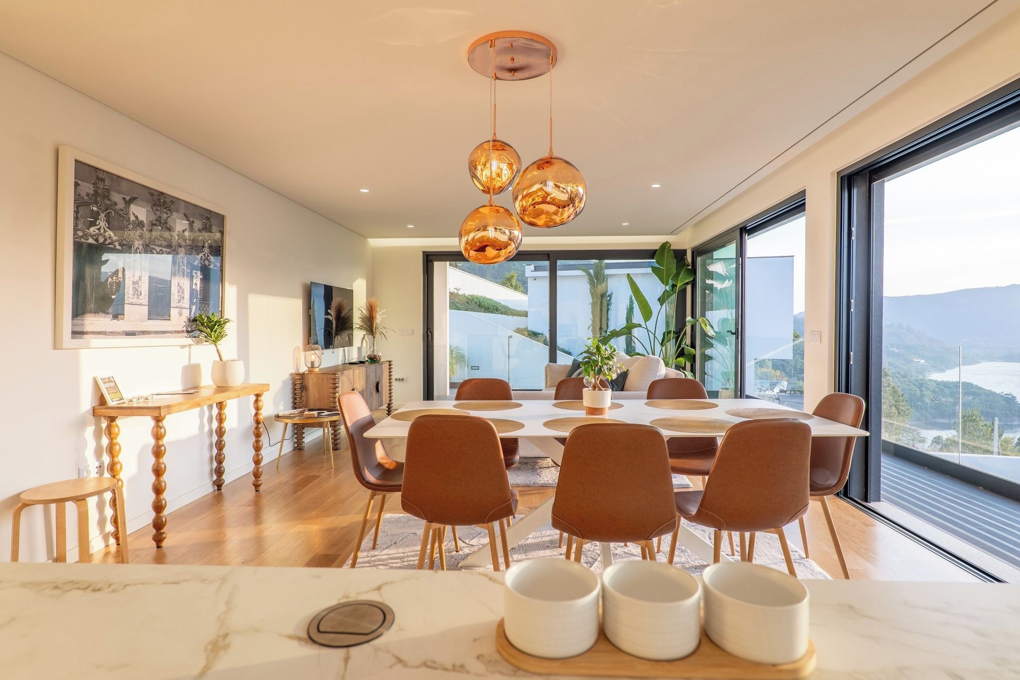 Una zona de menjador moderna amb una taula gran, cadires confortables i vistes a l'exterior.
