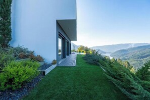 A modern house with a long, narrow driveway leading to a wooden deck, surrounded by lush greenery and overlooking a mountainous landscape. - Gerês Paradise (Vieira do Minho)