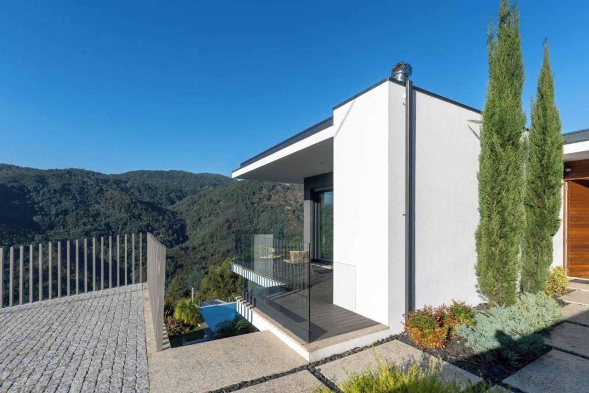 A modern house with a balcony overlooking a mountainous landscape.