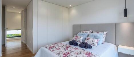 Un dormitorio moderno con una cama grande, paredes blancas y vistas al exterior.